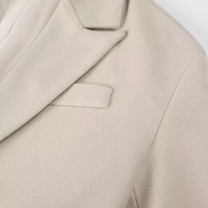 Détail du tissu en laine beige montrant les coutures du col et de la poche à rabat