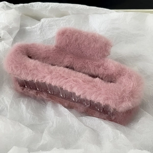 Macro detail of plush faux fur hair claw clip in soft smoky pink with fluffy texture
