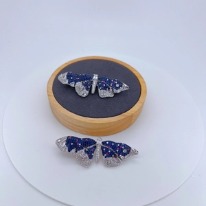 Détail macro d'une broche papillon avec zircons bleus et blancs sur support en velours