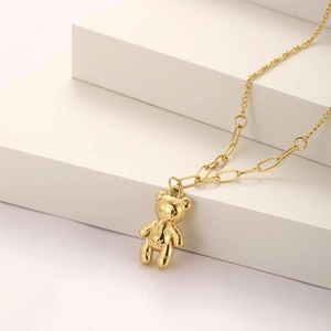 Macro detail of golden 3D bear pendant with embossed letters on a white display