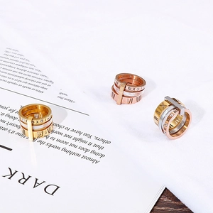 Close-up of stacked Roman numeral rings in gold, rose gold and silver finishes