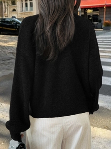Vue de dos d'un cardigan en maille noire décontracté et ample à manches longues en ville