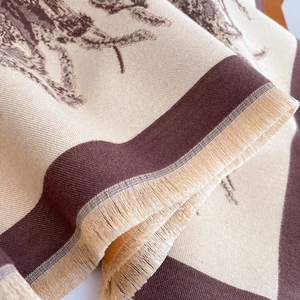 Close-up of beige and brown floral jacquard scarf with fine fringe tassels and thick texture