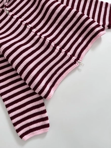 Dettaglio di un maglione a righe bordeaux con tessuto testurizzato e zip in metallo