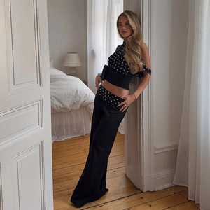 Detail of high-waist polka dot waistband on black wide-leg trousers for a chic summer look