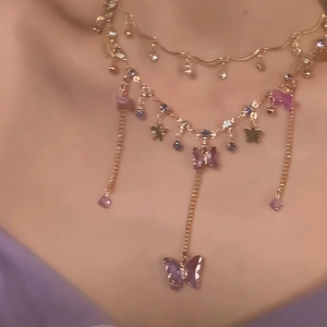 Detail of layered gold necklace featuring a purple butterfly pendant on a female model