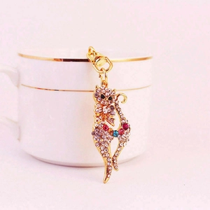 Elegant gold cat keychain with sparkling crystals and pink gemstone on white ceramic cup