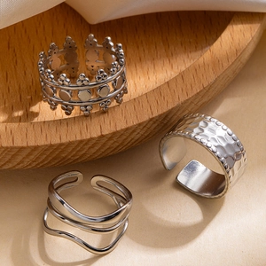 Set of irregular geometric stainless steel rings with textured silver finish on wood