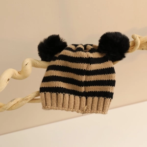 Dettaglio cappello invernale a maglia per neonati con righe e due pompon di pelliccia