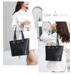 Detail of black crocodile embossed tote bag with gold metal trim and slim handles