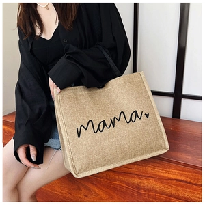 Lifestyle shot of a natural jute tote bag featuring mama text and heart detail