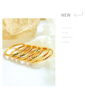 Close-up of stacked gold rings featuring rainbow zircon stones on a white background