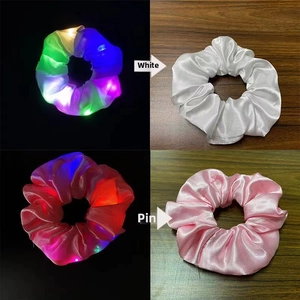 Detail view of white and pink LED scrunchies glowing in dark and on wood background