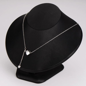 Minimalist silver heart tassel necklace displayed on a black neck mannequin
