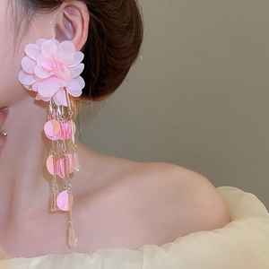 Detailed close-up of pink fabric flower earrings with sparkling tassels and sequins