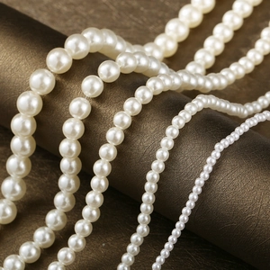 Detail view of round faux pearl beads in cream white showing various sizes and luster