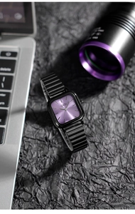 Detail of square purple brushed dial watch with black metal band on textured fabric