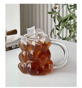 Detailed view of grape-shaped heat-resistant glass mug with handle and iced coffee