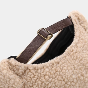 Detail of beige teddy fleece cap showing brown leather adjustable strap and metal buckle