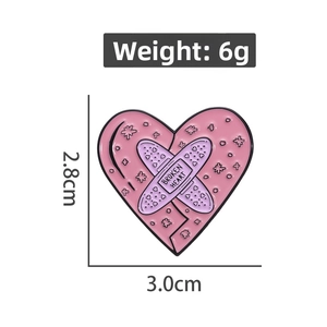 Detail of pink heart enamel pin with 3x2.8cm dimensions and broken heart lettering