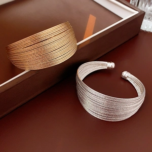 Close-up of gold and silver multilayer wire open bracelets on a leather tray