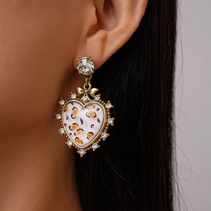 Side view of model wearing vintage leopard print heart earrings with sparkly rhinestones