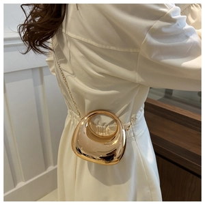 Sac rond tendance en métal doré avec chaîne porté par un mannequin en robe blanche