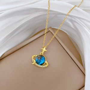 Macro shot of gold planet necklace with blue nebula sphere and crystal ring detail