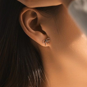 Vintage textured S925 sterling silver bow stud earrings worn by a model in macro view