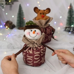 Detail of Christmas drawstring gift bags featuring snowman and reindeer designs with JOY print