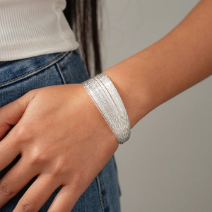 Detail of silver multi-layer geometric chain bracelet on model's wrist in daily setting