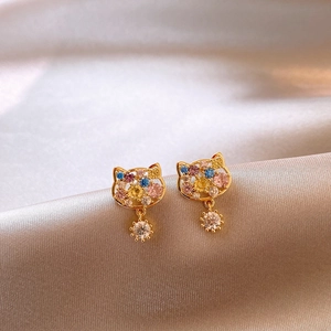 Detailed macro view of gold plated cat stud earrings with colorful cubic zirconia on silk