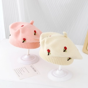 Detailed macro view of soft knit pumpkin berets with 3D floral embroidery and pointed top
