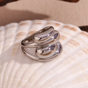 Macro shot of silver stainless steel ring with water drop design on a white seashell