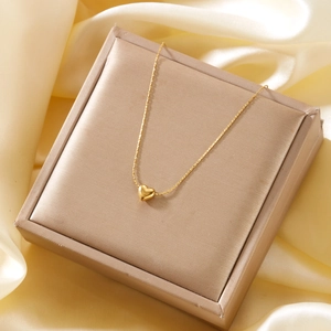 Close-up of heart pendant gold necklace displayed on premium silk and gift box