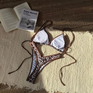 Flat lay of leopard print bikini with halter top and tie-side bottoms on a rug