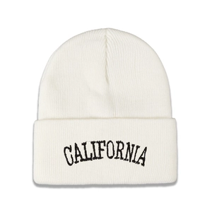 Close-up of black CALIFORNIA embroidery on a white minimalist knitted beanie hat