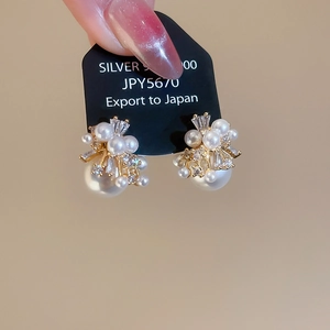 Macro shot of silver pearl cluster earrings with sparkling zircons on jewelry card