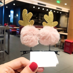 Close-up of pink pompom and gold glitter reindeer antlers on a metal hair clip