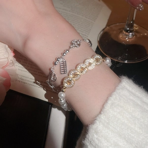 Detail of layered Chinese style bracelets with copper coin, abacus charms and white pearls