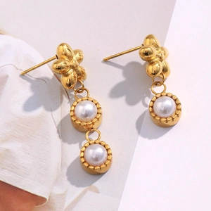Detailed view of 18K gold plated asymmetric flower earrings with hanging imitation pearls