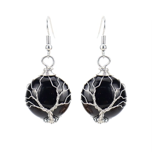 Detail of handmade wire wrapped tree of life earrings with black natural crystal stones