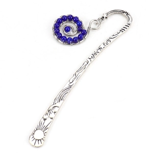 Detail of silver metal bookmark with sun and star relief and blue bead spiral charm