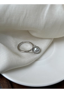 Primo piano di anello in argento S925 con perla grigia su morbida seta bianca