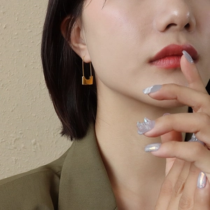 Polished gold paperclip earrings for women styled with professional attire on a model