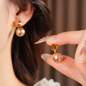 Detail of French vintage gold earrings with amber gemstones and pearls on model