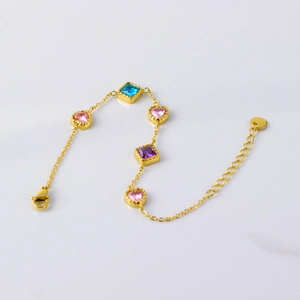 Close-up of gold chain bracelet with colorful heart and square zircon stones
