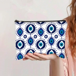Handheld Evil Eye travel makeup bag featuring blue and white printed canvas with zipper