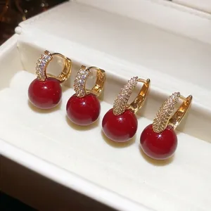 Elegant gold hoop earrings with deep red resin drop and sparkling zircon accents