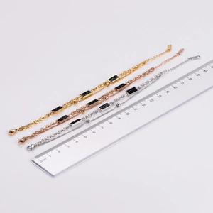 Three-piece stackable metal bracelets in gold, silver, and rose gold with black charms